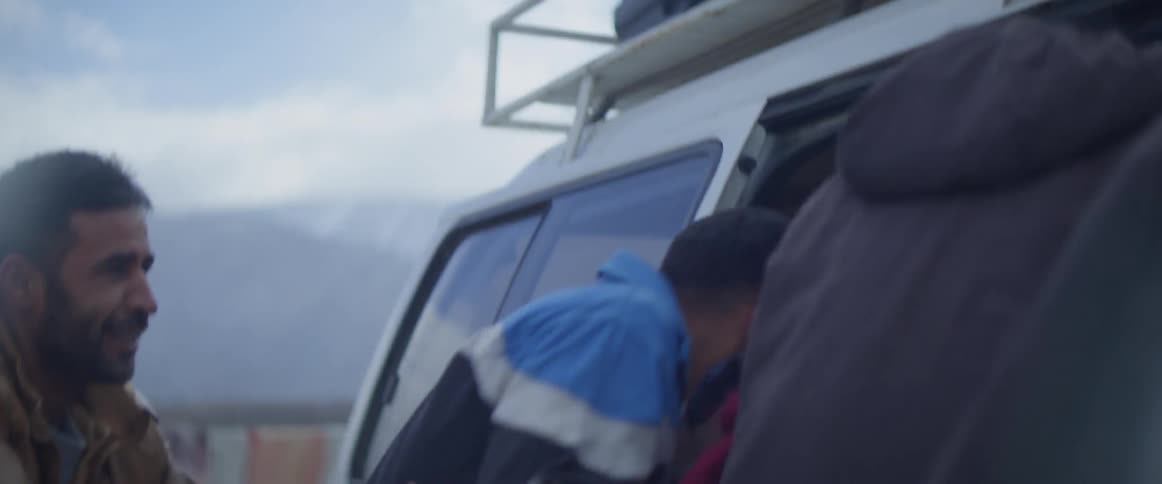 Group of people run towards a van and begin to climb inside