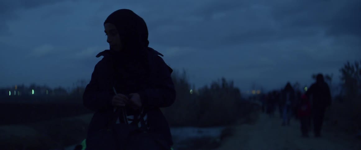 A young girl carries her bag outside at night