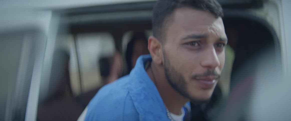 Man raises his head as he stands near a vehicle