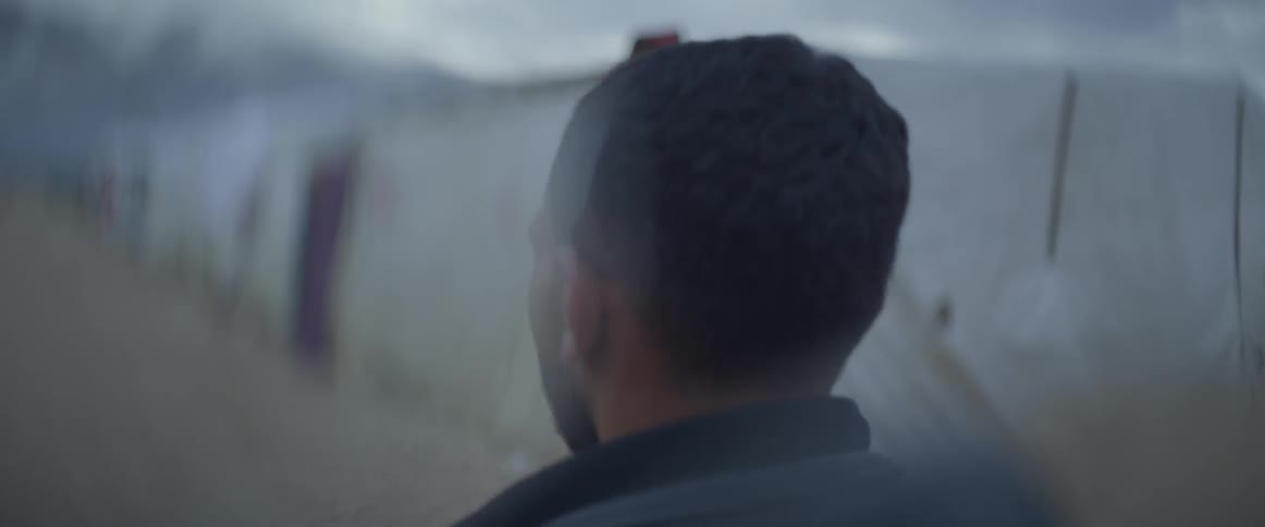 A man walks past shacks and tents in a village