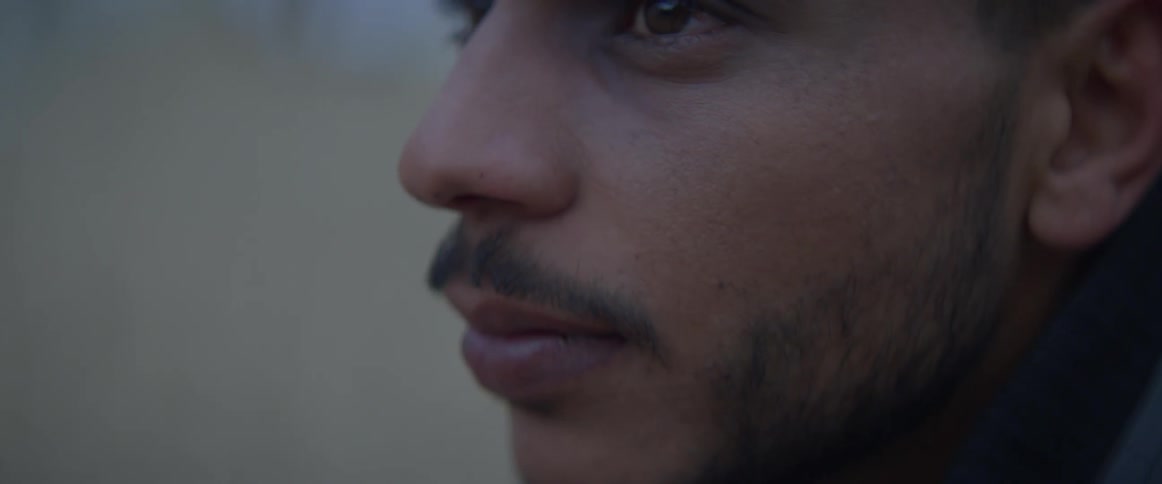 Man with a mustache blinks his eyes then looks down