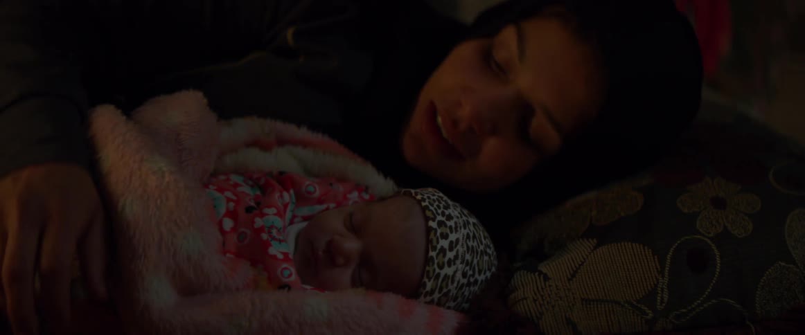 A woman holds a baby as she is laying down