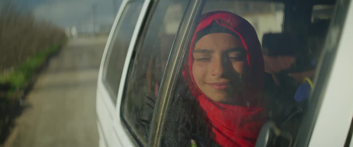 Woman wearing a red scarf travels as a passenger in a white van