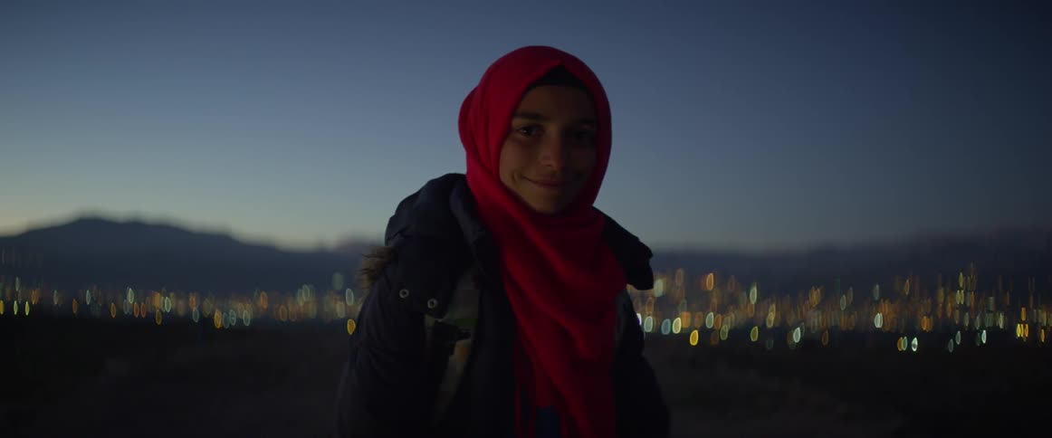 A woman smiles on a field at sunset