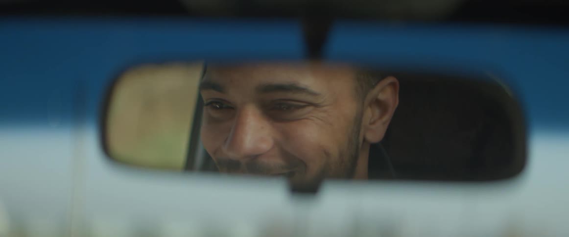 The man looks to the side smiling as he drives
