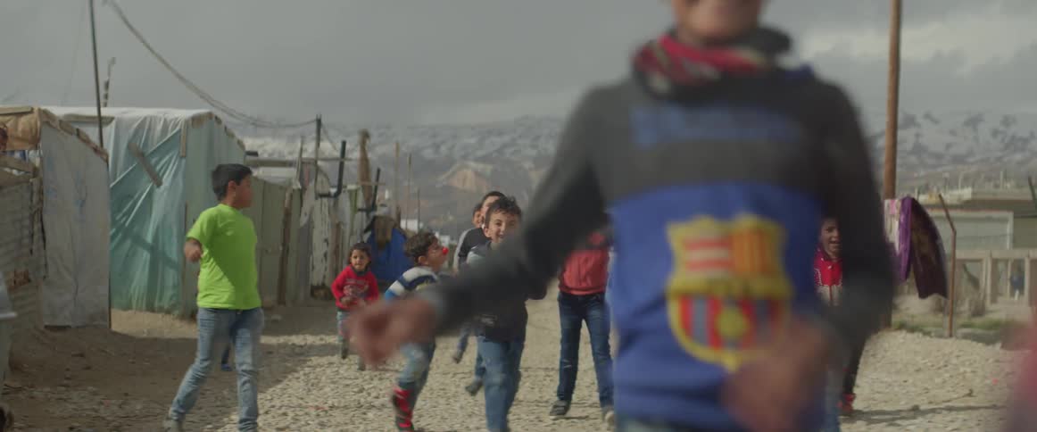 Children run through a village of tents on a sunny day