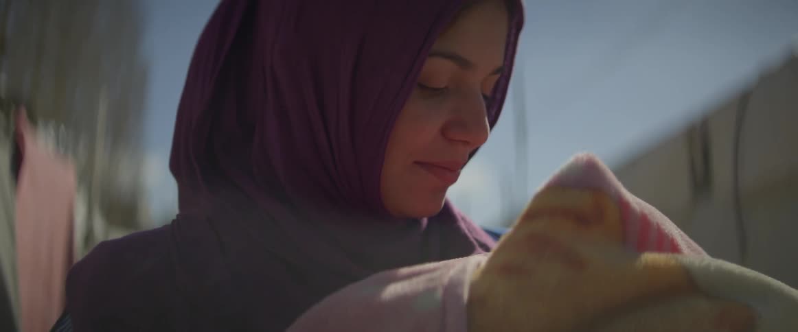 Woman looks down at a baby wrapped in a blanket