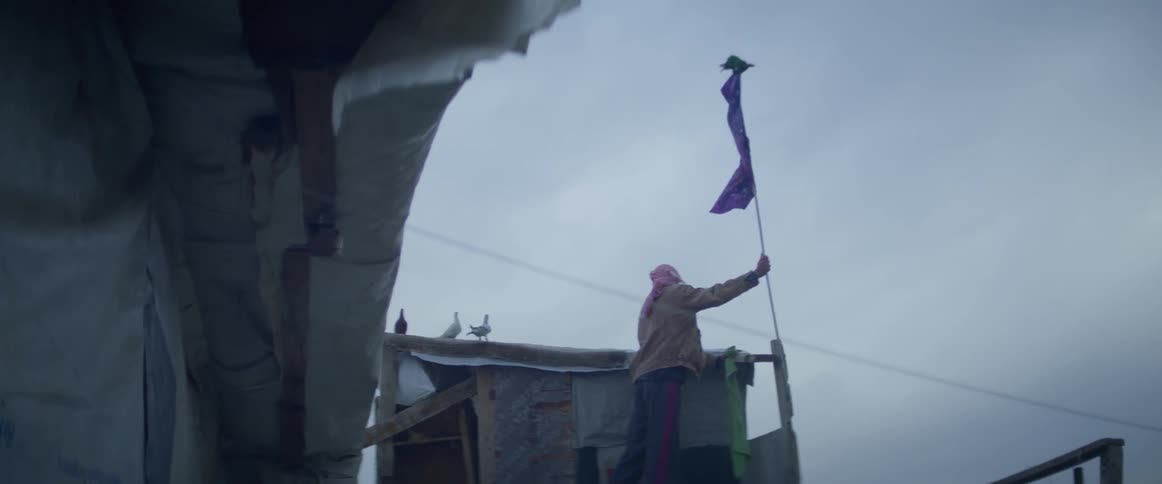 Man waves a piece of fabric tied to the end of a long pole