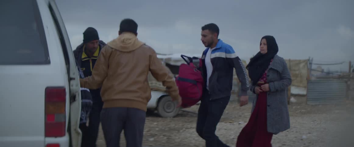 Group of people run toward a white van and get in