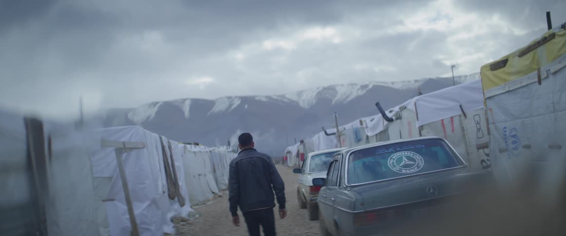 A man is walking through a refugee camp on a winter day