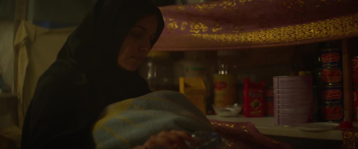 The woman removes a bottle from the shelf