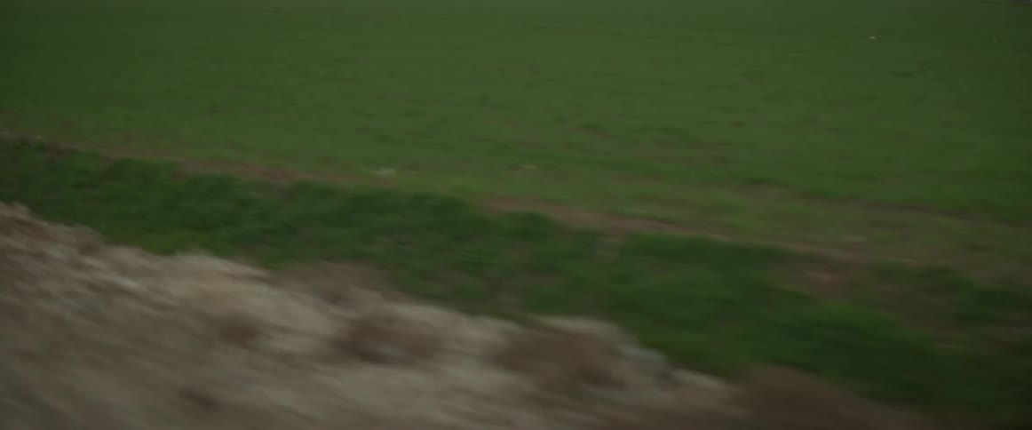 Drainage ditch between a dirt road and a field