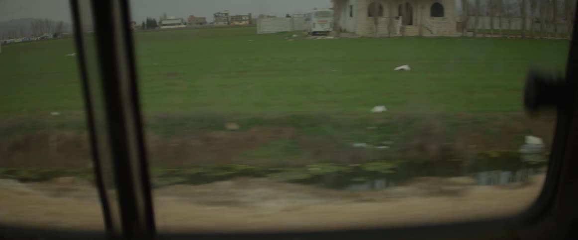 Vehicle travels down the road next to a field
