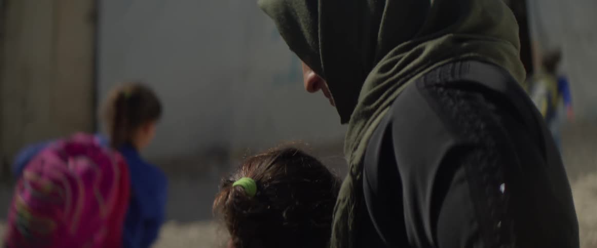 Woman watches school children pass by and gives one child a hug