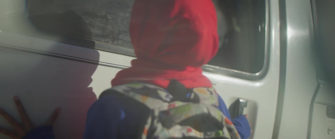 Smiling woman wearing a backpack looks into a white vehicle