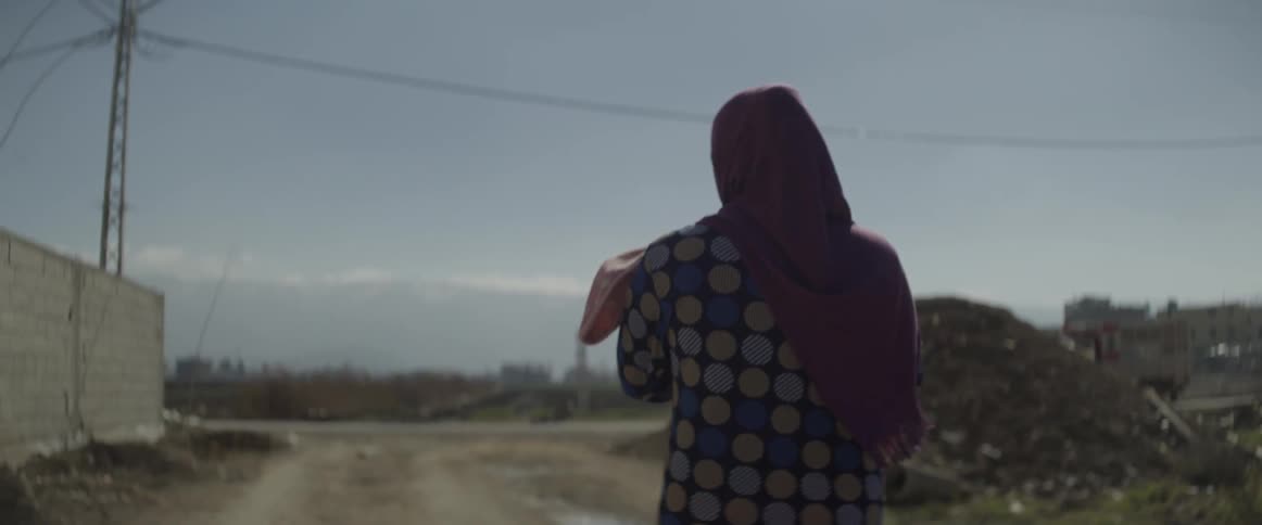 Woman walks outside on a sunny day carrying a baby