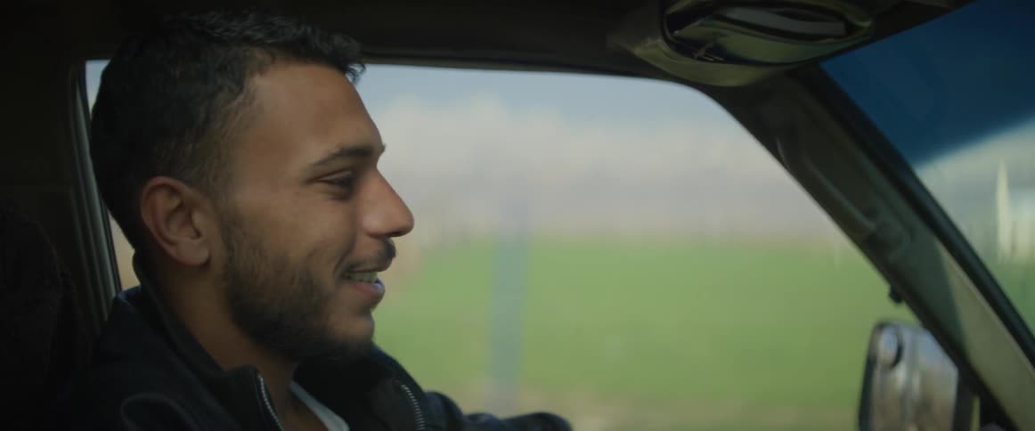 A man smiles and laughs as he drives