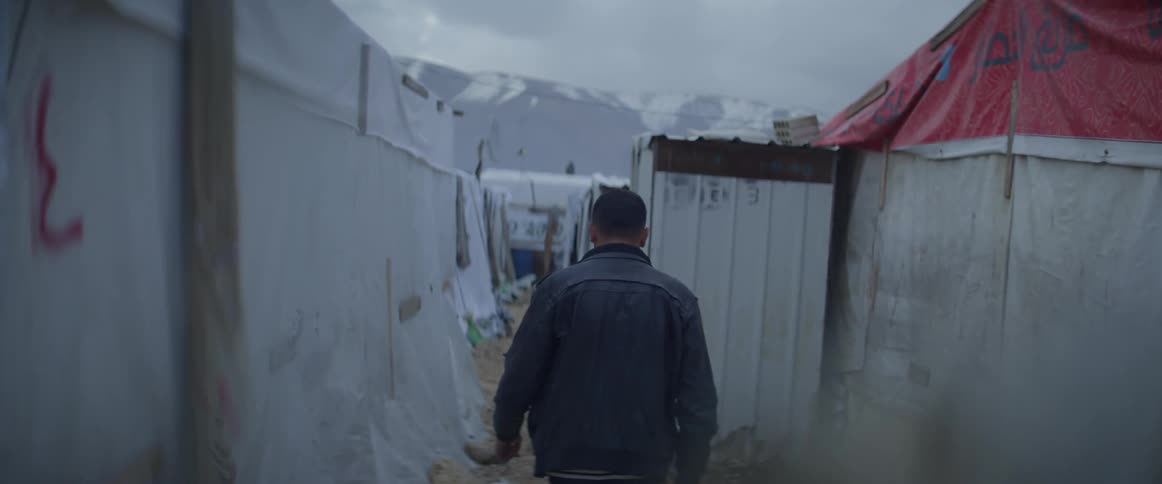 Man walks through a row of tents outside on a cloudy day