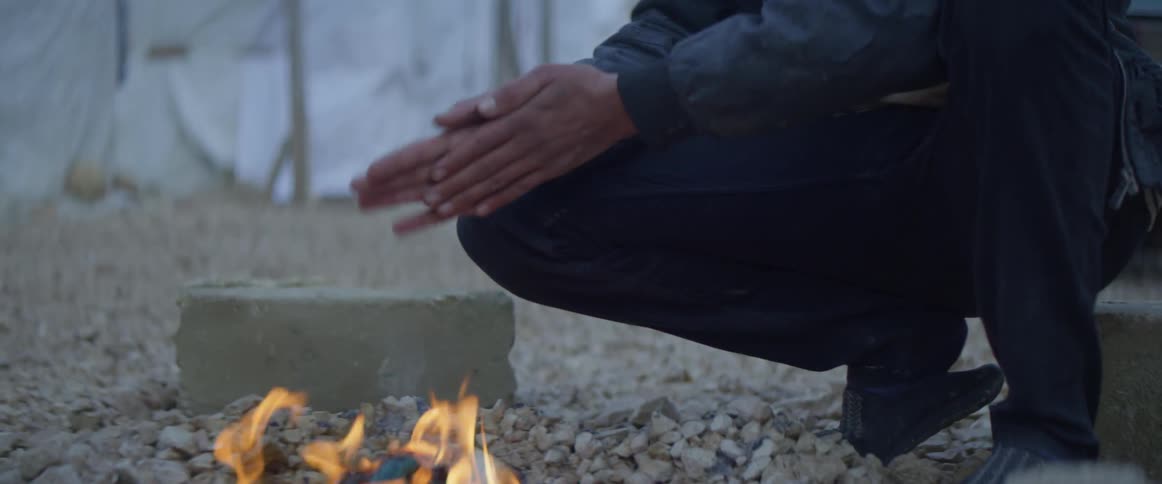 A man warms his hands over the campfire