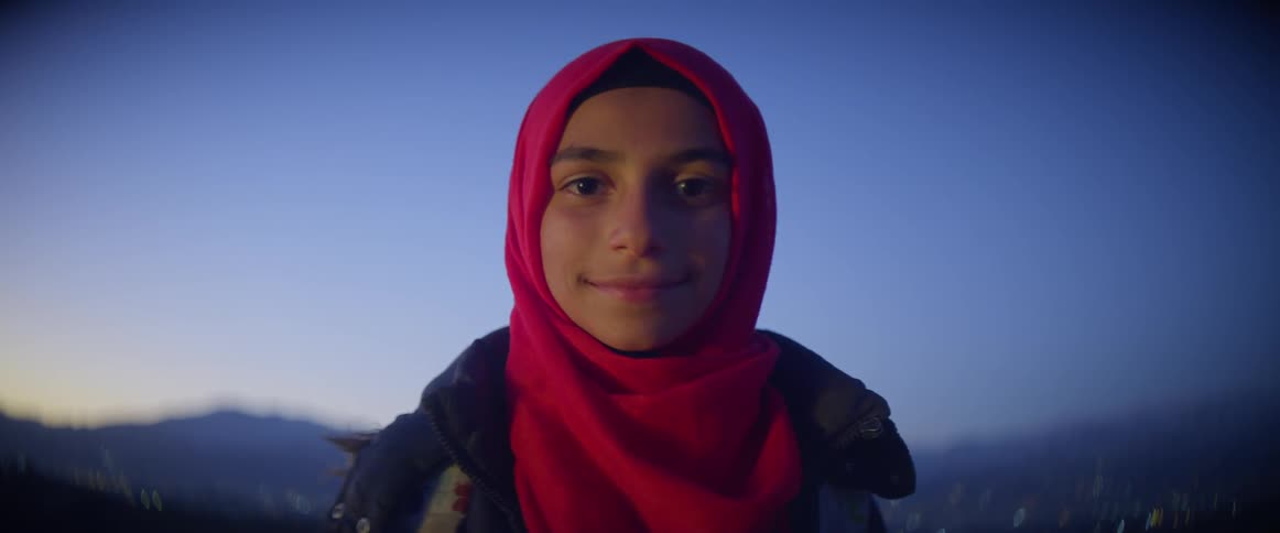 Woman wearing a red scarf walks then lifts her head and smiles