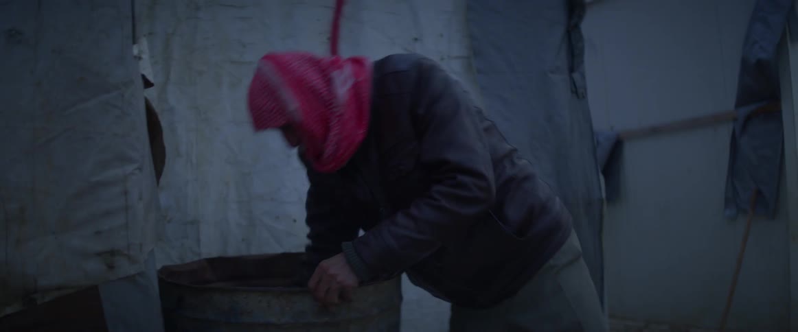 Person digs into a bin and takes something out to put on a fire