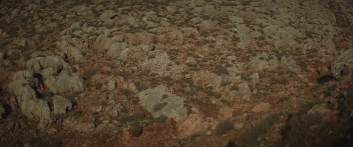 The hill is covered with many rocks and grass