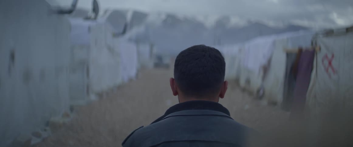 A man walks down a row of shacks in a village