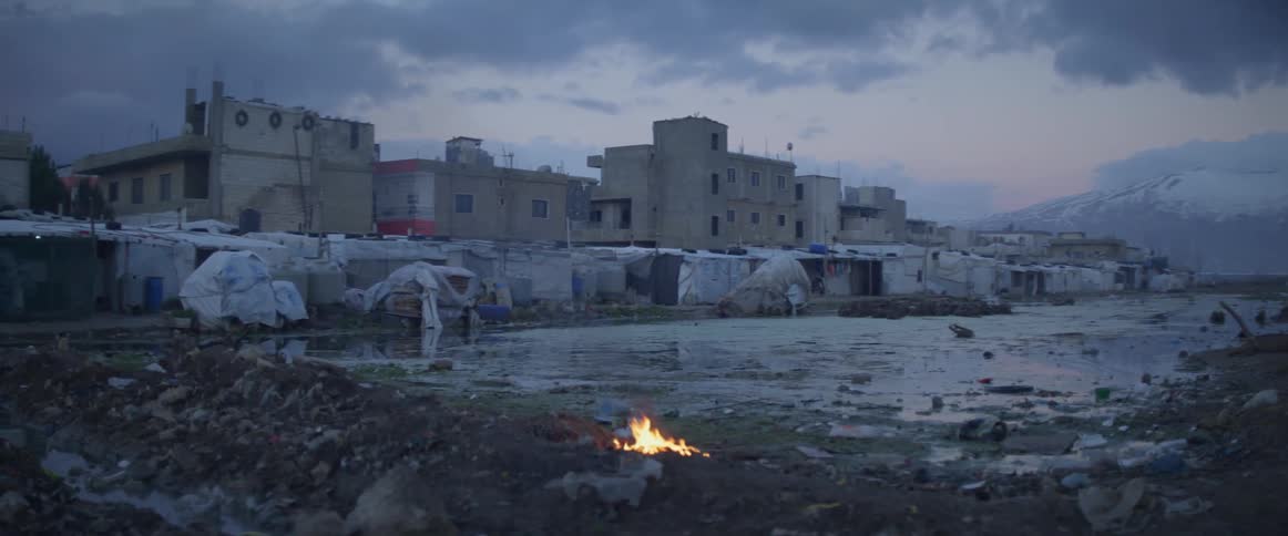 Small fire burns outside a small village on a cloudy day