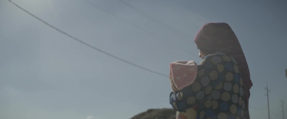 A woman walks outside carrying her child