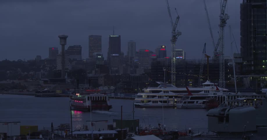 Large cruise ship sits in the water as a ferry passes before a large city