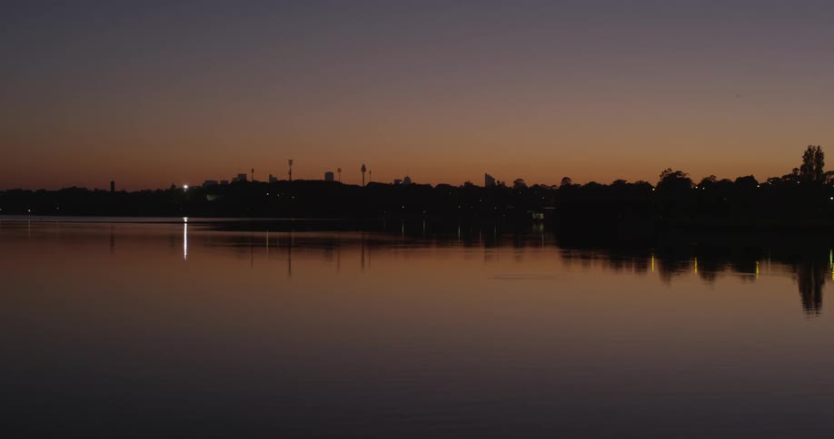 View of a town with trees over the water at sunset