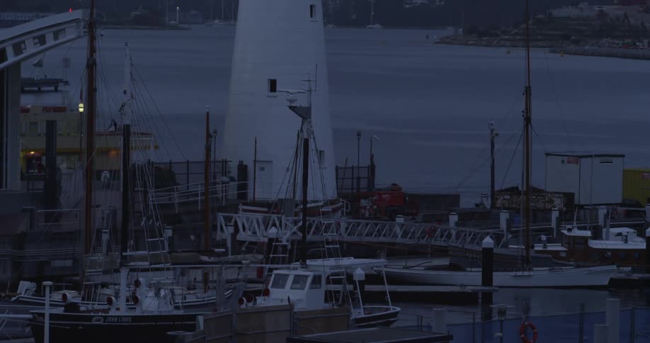 A ferry moves past a lighthouse and marina