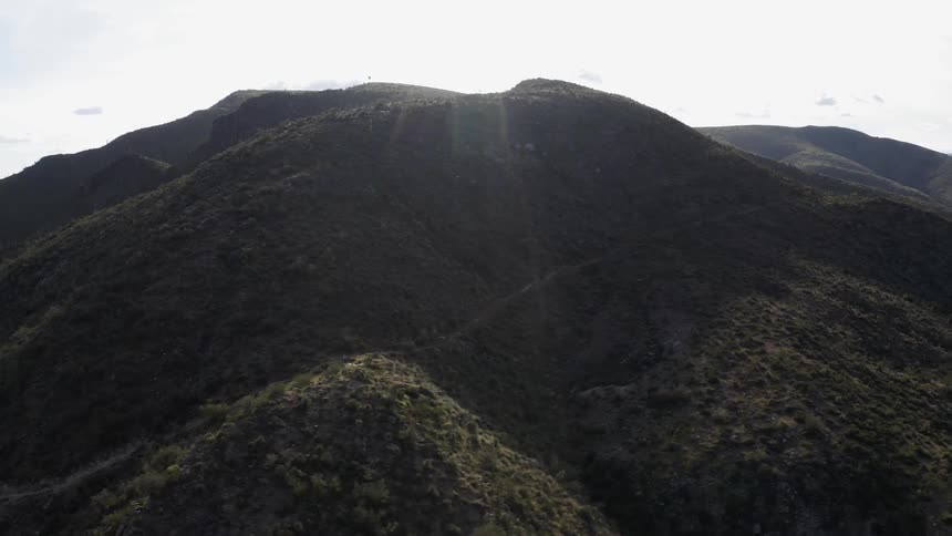 Sun shines over grassy rocky mountains