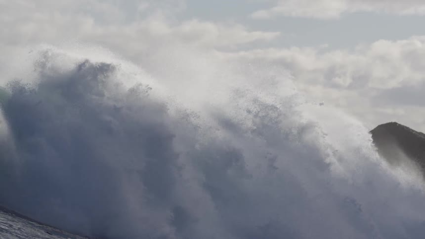 Large ocean wave surges and crashes on a cloudy day