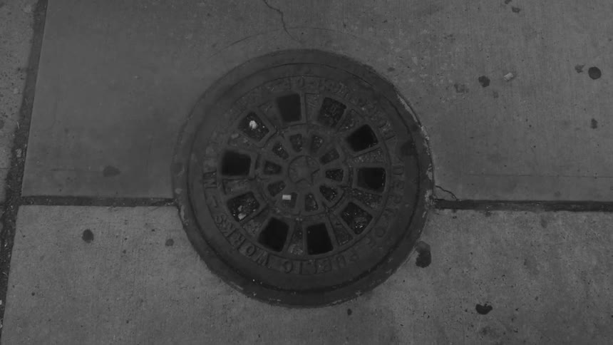 Smoke rises from the sewer lid in a sidewalk