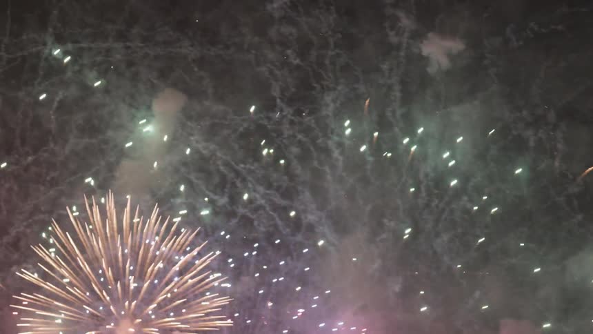 Fireworks and smoke fill a night sky