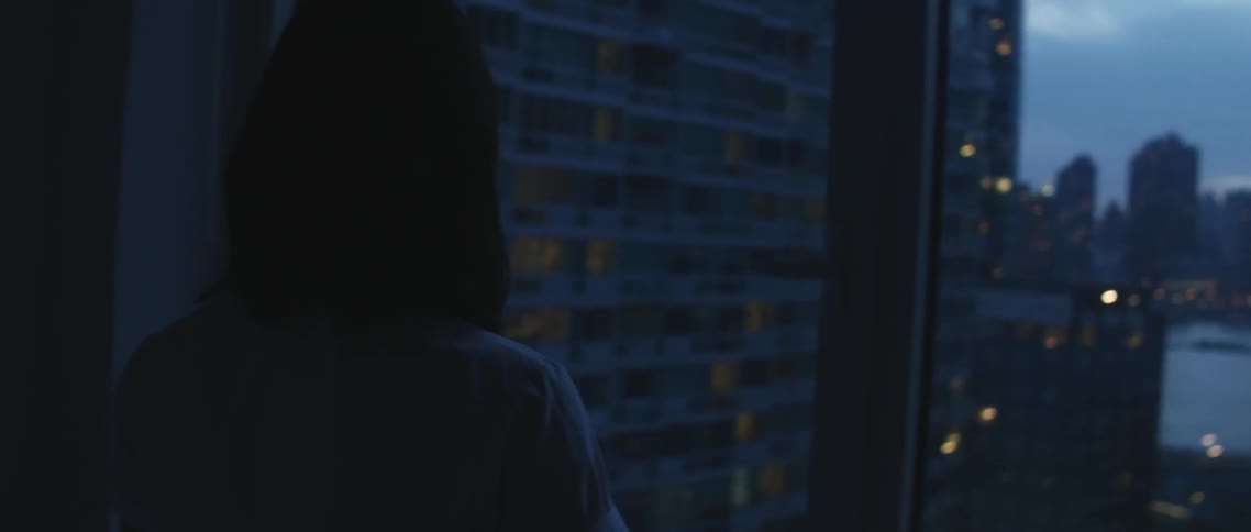 Woman standing in front of a window looking at a city