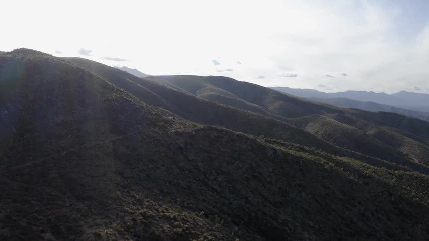 Hills sit under a cloudy blue sky