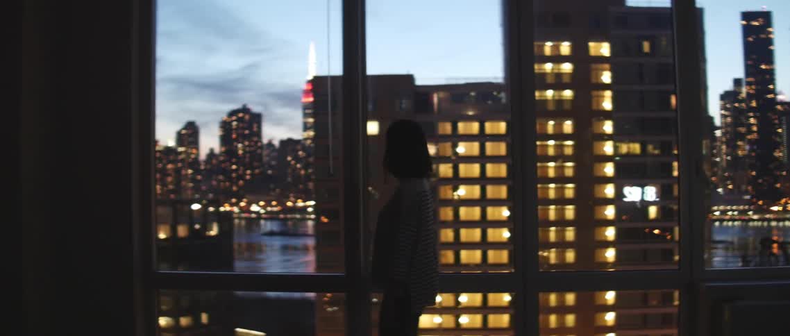 Woman walking along a large row of windows overseeing a city