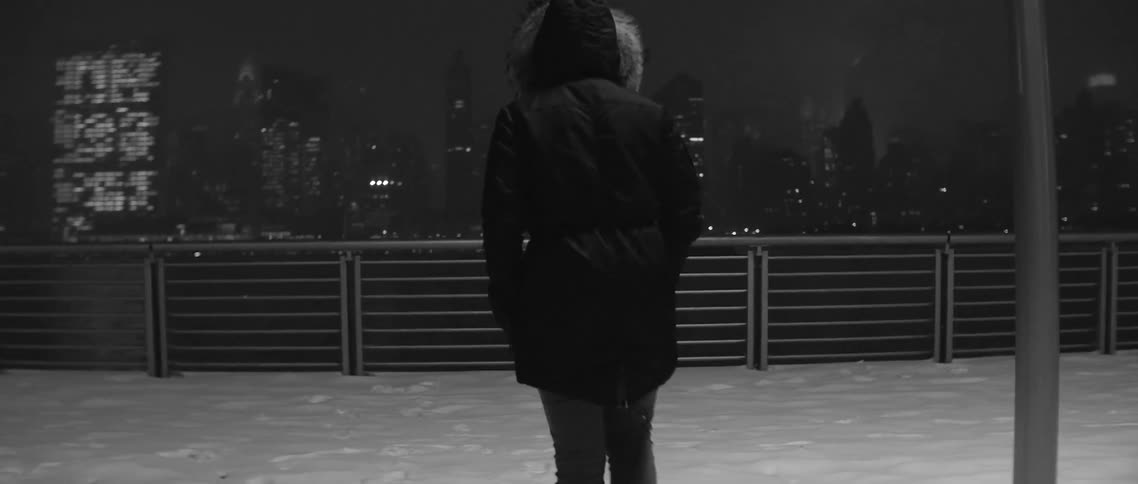 A woman walking through snow towards skyscrapers