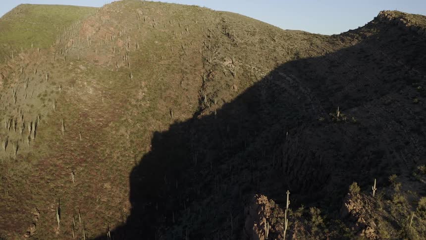 The tall hill is covered halfway with shadow
