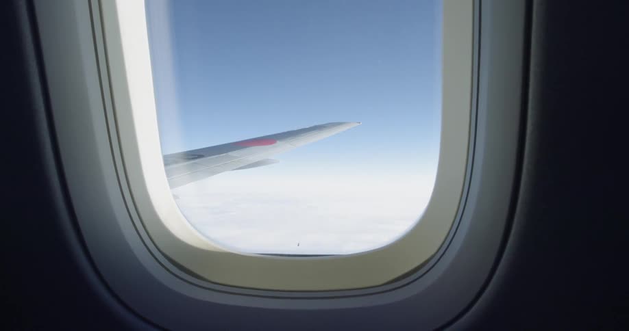 Airplane wing seen through cabin window mid-flight
