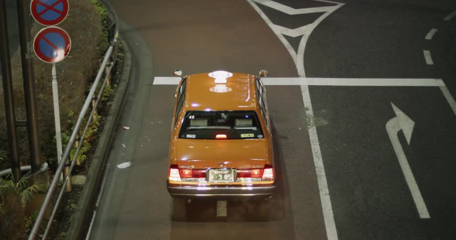 A taxi cab is sitting at an intersection in an asian city at night