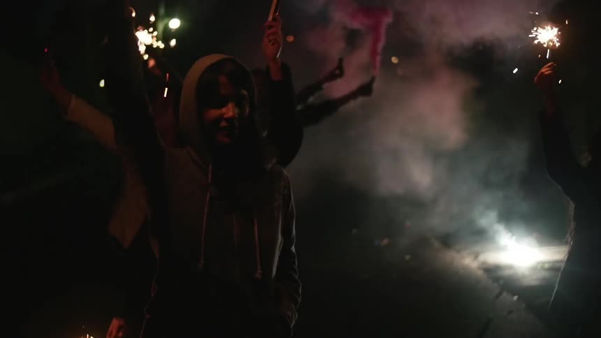 People standing outside at night lighting off sparklers