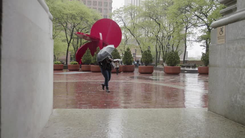 Person walks in a city square in the rain holding an umbrella