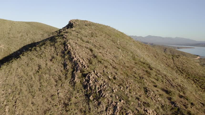 The tall hill by the water is covered with grass