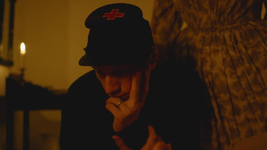 A soldier leans over inside a candle lit room