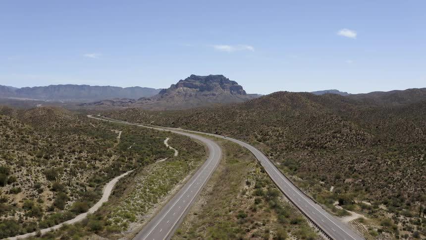 Two winding roads lead towards the mountains ahead