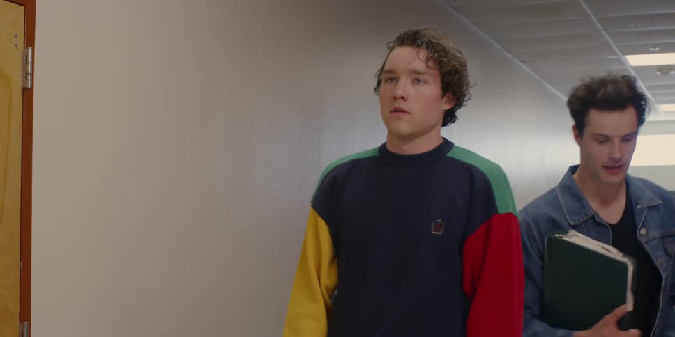 A boy pauses in a hallway as others walk by