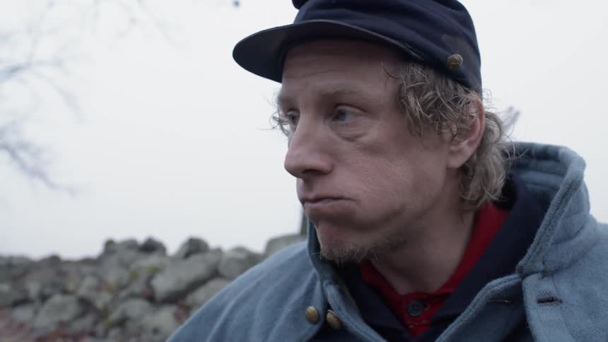 Man eats and wipes his face with a rag outside on a cloudy day